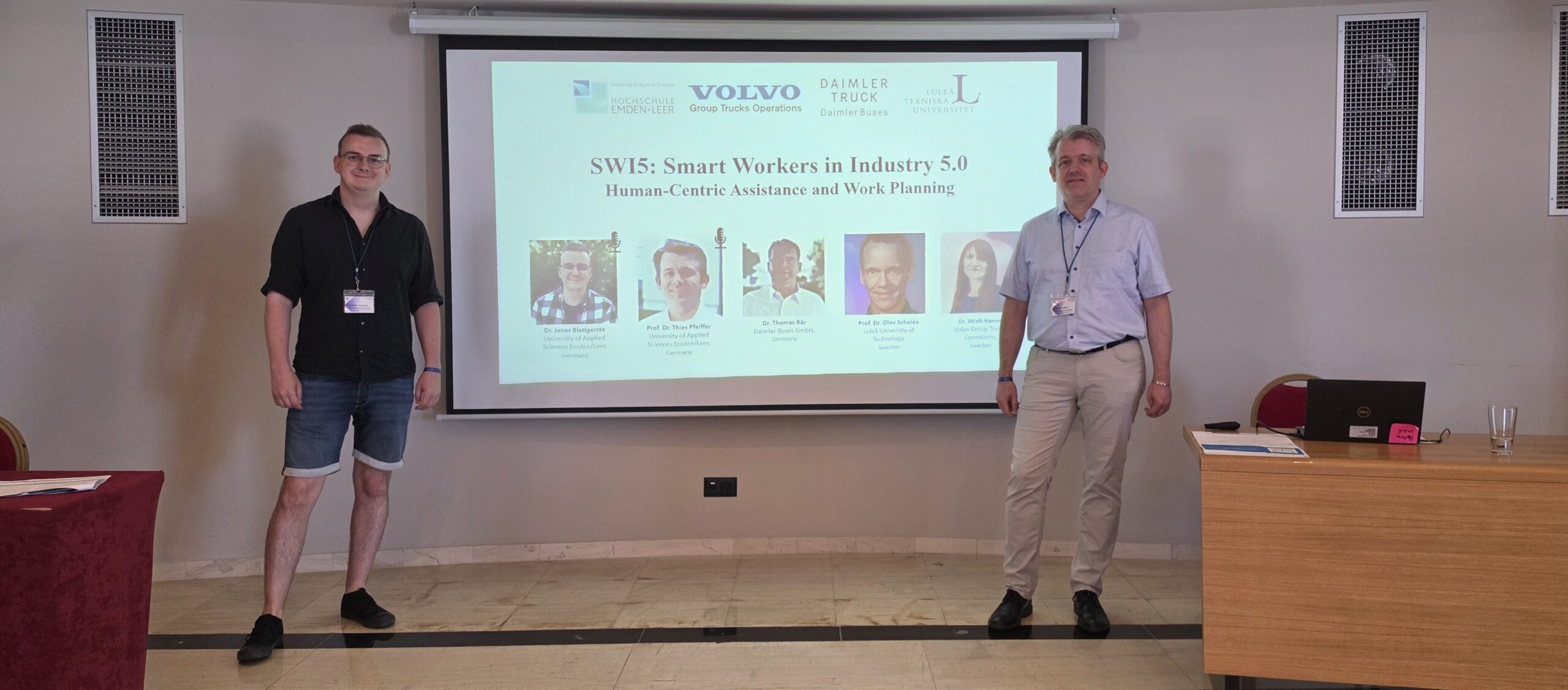 During the opening of the SWI5 workshop on Smart Workers in Industry 5.0, organizers Dr. Jonas Blattgerste and Prof. Dr. Thies Pfeiffer are standing in front of the title page presentation.